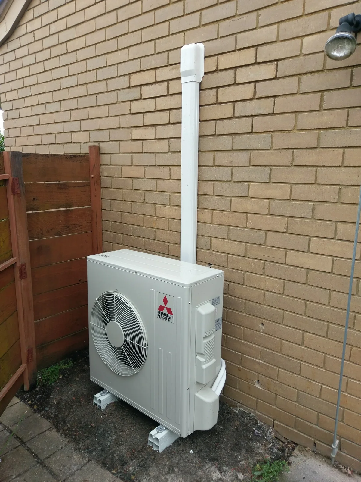 Mitsubishi Electric outdoor unit installed beside a side gate