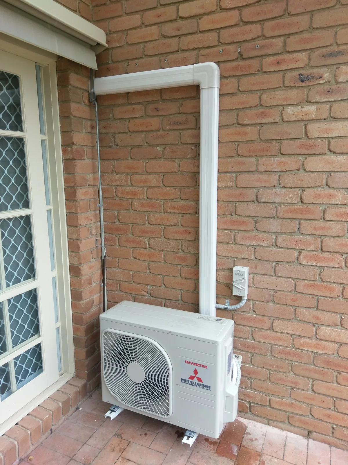 Mitsubishi Electric outdoor unit installed beside a window