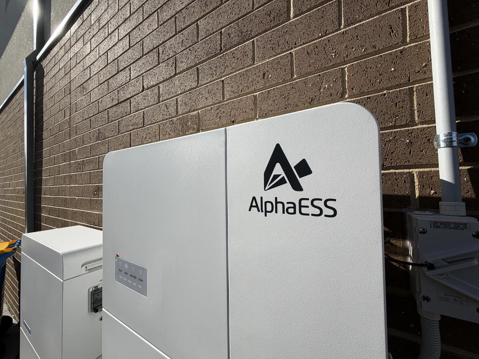 AlphaESS home battery installed on a brick wall beside the meter