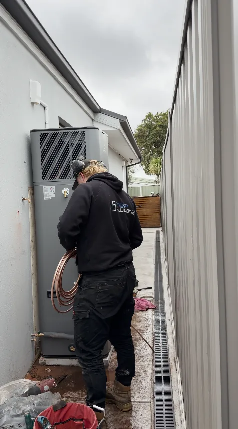 Plumber running copper to an Emerald heat pump along a side path