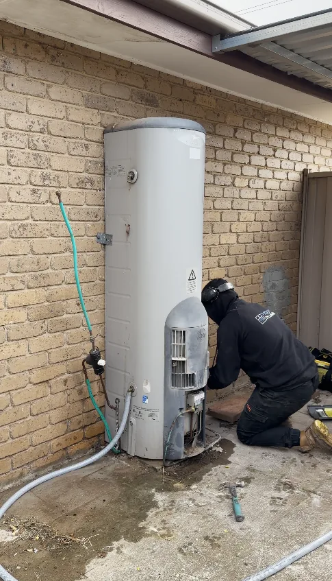 Old gas storage hot water unit being disconnected before a heat pump install