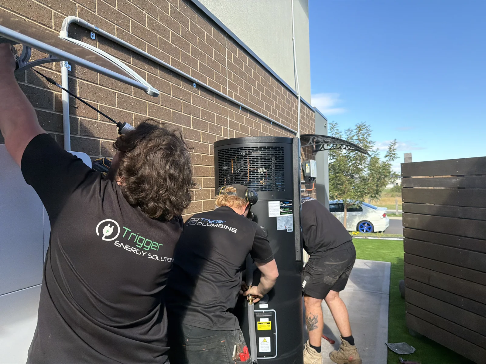 Trigger Energy Solutions and Trigger Plumbing crew installing a heat pump hot water system together at a Melbourne home